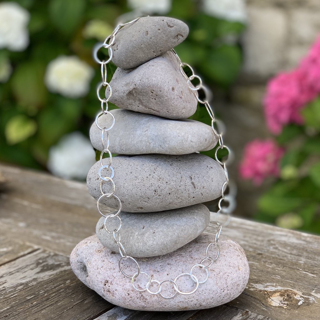 Caldera Cirque Link - 20" handmade hammered silver necklace - displayed on rocks