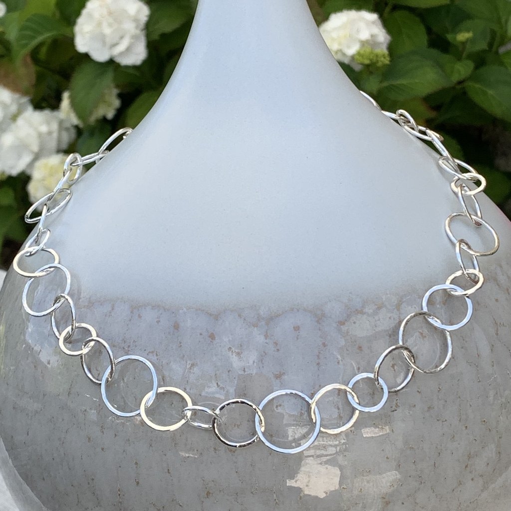 Caldera Cirque Link  - 20" handmade hammered silver necklace - displayed on vase
